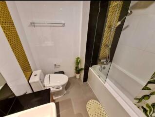 Modern bathroom with black and gold tiles, shower, and toilet