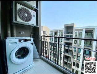 Apartment balcony with washing machine and outdoor air conditioning unit overlooking other buildings