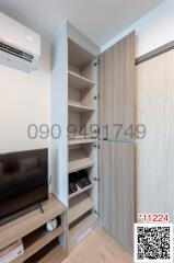 Compact living room interior with open wooden shelving unit and TV