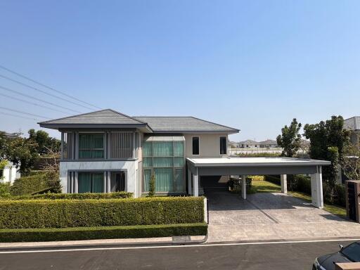 Modern two-story house with large windows and carport