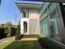 Modern residential house exterior with large glass windows and landscaped garden