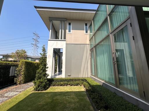 Modern residential house exterior with large glass windows and landscaped garden