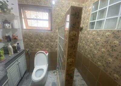 Compact tiled bathroom with floral patterns and a shower area