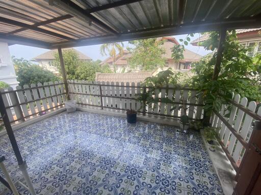 Spacious covered patio with patterned tile flooring and white fencing