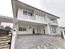 Spacious two-story residential house with white exterior, balcony, and large driveway