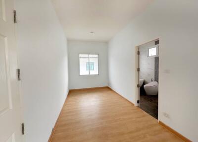 Empty bedroom with wooden flooring and adjacent bathroom