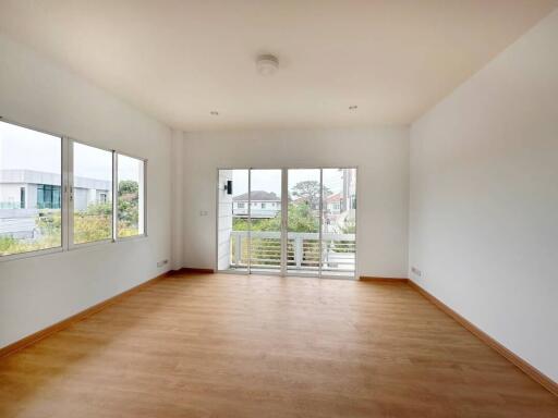 Spacious and well-lit living room with wooden flooring and balcony access