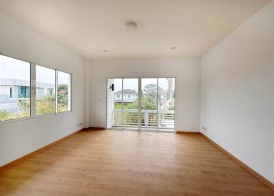 Spacious and well-lit living room with wooden flooring and balcony access