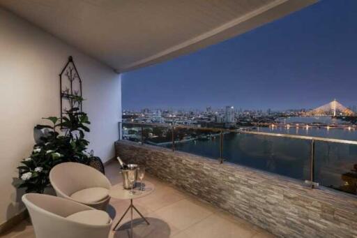 Spacious balcony with comfortable seating overlooking the city skyline at night