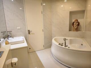 Modern bathroom with white marble tiles featuring a whirlpool bathtub and enclosed glass shower