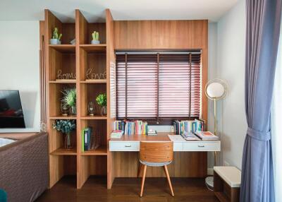 Home office with a modern desk, bookshelf, and natural light