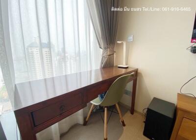 Bright bedroom with city view, featuring a wooden work desk and a modern chair