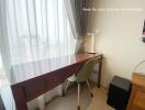 Bright bedroom with city view, featuring a wooden work desk and a modern chair