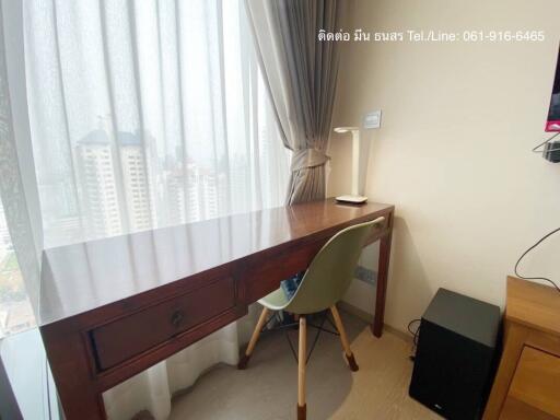 Bright bedroom with city view, featuring a wooden work desk and a modern chair