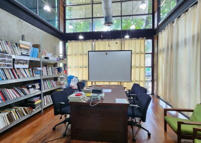 Spacious home office with high ceiling, large windows, and a bookshelf