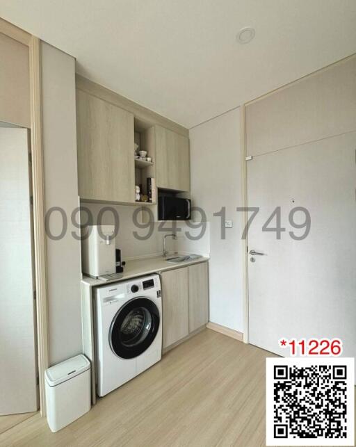 Compact modern kitchen area with appliances and white cabinetry