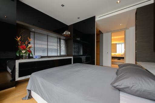 Modern bedroom with a large bed, hardwood floors, and an en-suite bathroom