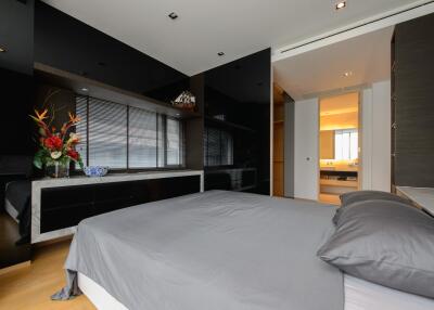 Modern bedroom with a large bed, hardwood floors, and an en-suite bathroom