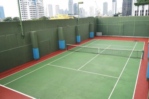 Tennis court in a residential building with city skyline in the background