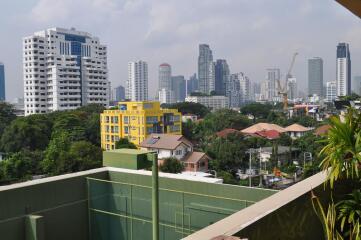 Cityscape view from a balcony showing urban environment with buildings and greenery