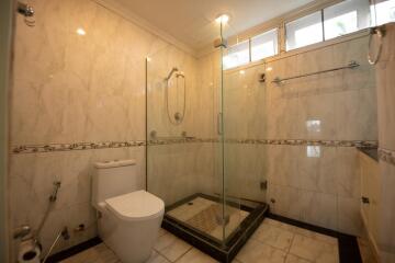 Spacious bathroom with modern glass shower enclosure and marble tiles