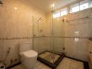 Spacious bathroom with modern glass shower enclosure and marble tiles