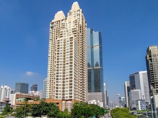 Tall residential skyscraper amidst urban cityscape with clear blue sky