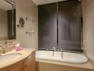 Modern bathroom with a bathtub and shower combo, well-lit vanity area, and wall-mounted mirror