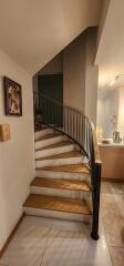 Elegant staircase with wood finish and black wrought iron banister in a home interior