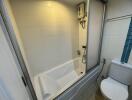 Modern bathroom with shower and bathtub combo, white tiles, and natural light