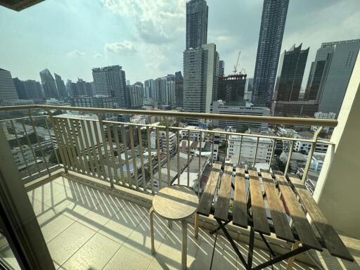 Spacious balcony with city skyline view featuring wooden furniture