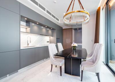 Modern kitchen with integrated appliances and adjacent dining area with stylish table and chairs