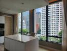 Modern kitchen with large windows overlooking city buildings