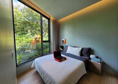 Modern bedroom with large window overlooking greenery