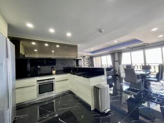 Modern kitchen with integrated appliances and open floor plan leading to a dining area