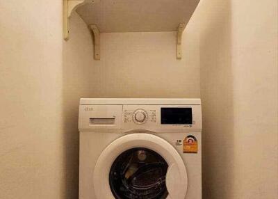 Compact laundry area with an LG washing machine and wall-mounted shelves