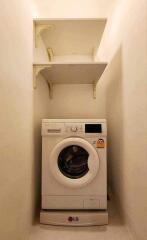 Compact laundry area with an LG washing machine and wall-mounted shelves