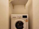 Compact laundry area with an LG washing machine and wall-mounted shelves