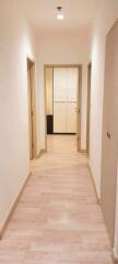 Brightly lit hallway with wooden flooring leading to a door