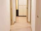 Brightly lit hallway with wooden flooring leading to a door