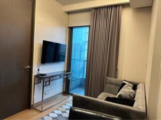 Modern living room interior with comfortable sofa, flat-screen TV, and sliding door leading to balcony