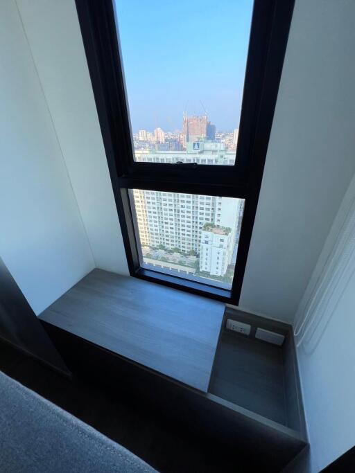 City view from a high-rise building window with seating area