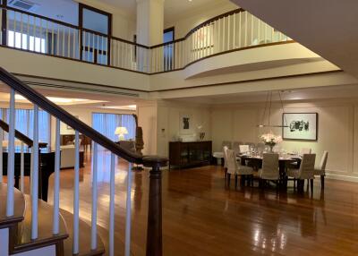 Spacious interior of a luxury house with an open floor plan, including a dining area and upper-level railing