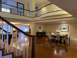 Spacious interior of a luxury house with an open floor plan, including a dining area and upper-level railing