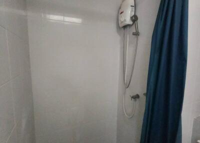 Compact bathroom with electric shower and curtain