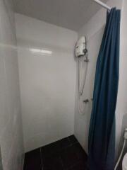 Compact bathroom with electric shower and curtain