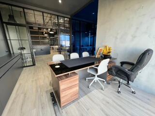 Modern home office with glass walls and wooden furniture