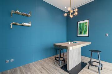 Modern kitchen corner with blue walls, wooden floor, and designer lighting