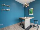 Modern kitchen corner with blue walls, wooden floor, and designer lighting