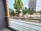 Spacious balcony with a view of surrounding area, including greenery and urban landscape